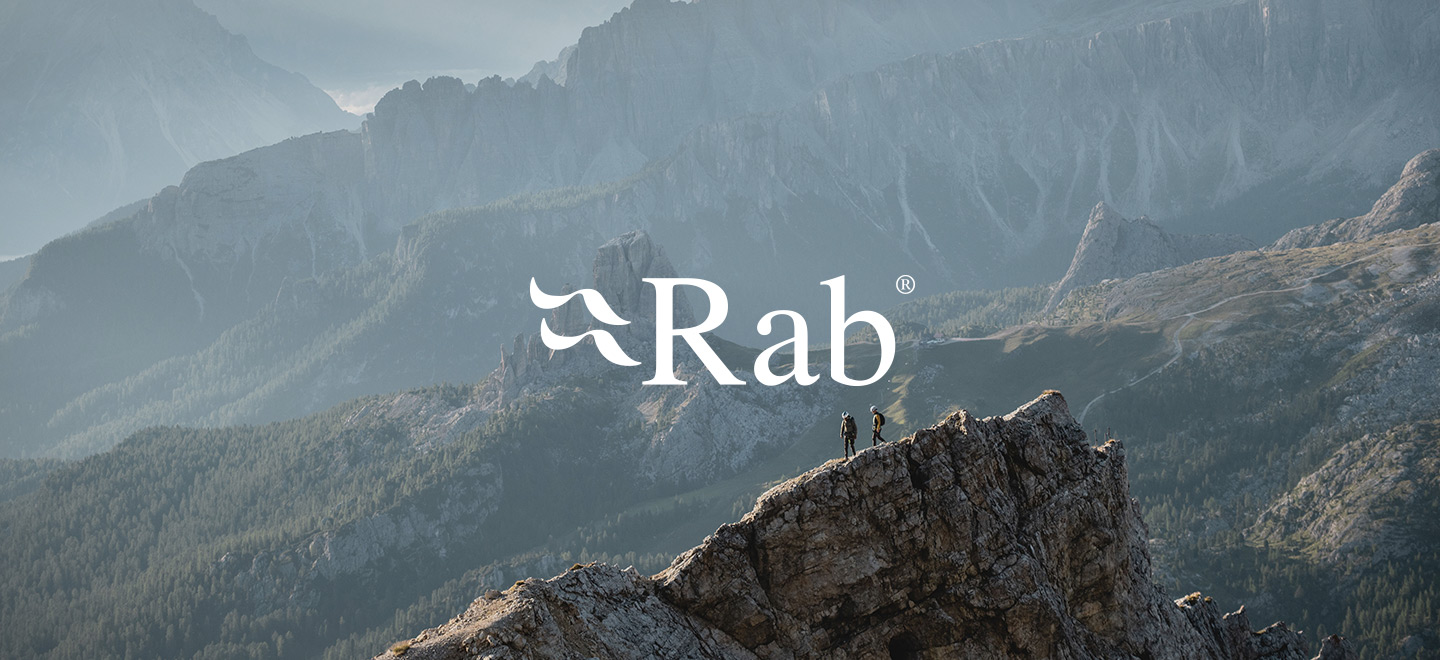 man and a woman on top of a mountain with the Rab logo underneath
